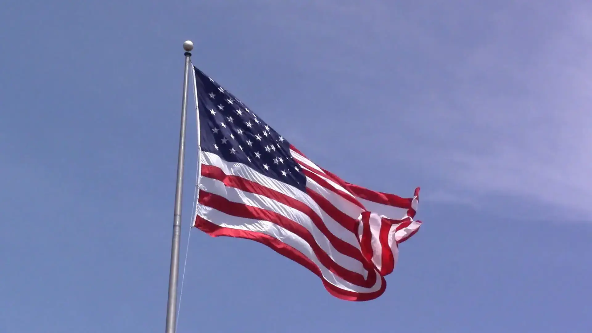 A flag flying in the wind on top of a pole.